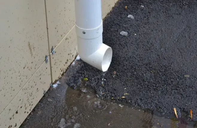 Bajante en mal estado goteando agua junto a la fachada, origen de humedad por filtración en Huelva
