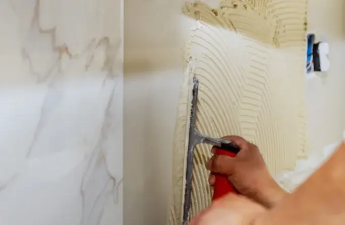 Aplicación de cemento cola para revestimiento de pared con porcelánico de gran formato en Huelva